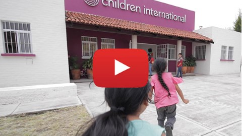 a group of children walking in front of a Children International community center